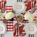 Dinner table setting with lobster-themed placemats, white plates, and silverware on a red and white checkered tablecloth.