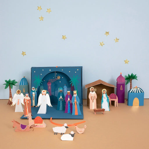 Colorful nativity scene with characters and elements on a beige surface and light blue background.
