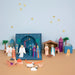 Colorful nativity scene with characters and elements on a beige surface and light blue background.
