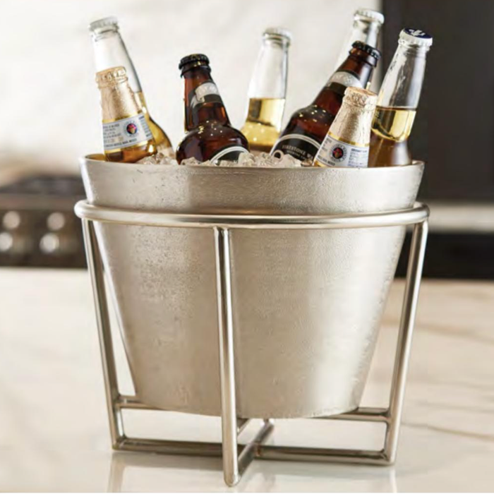 Metal ice bucket with bottles of beer on a light surface