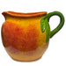Ceramic pitcher with a green handle shaped like a leaf on a white background