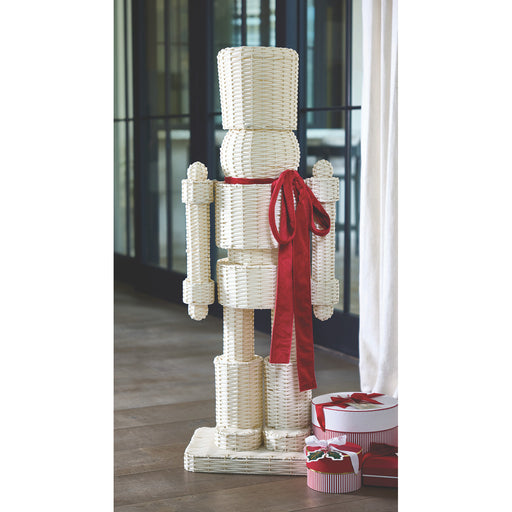 Decorative wicker Nutcracker figure with a red ribbon in an indoor setting.