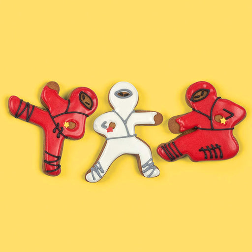 Three cookie cutters shaped like Ninjabread Men on a yellow background
