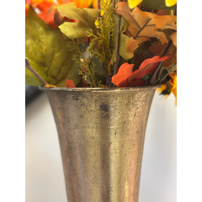 Decorative arrangement of autumn leaves in a rustic metal vase on a white background