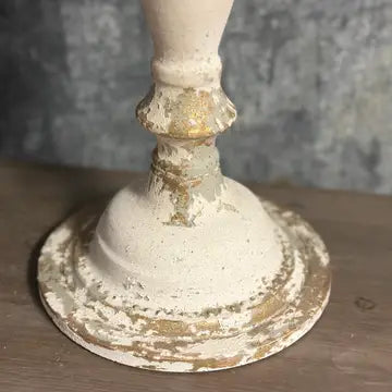 Vintage candle holder with a rustic finish on a wooden surface.