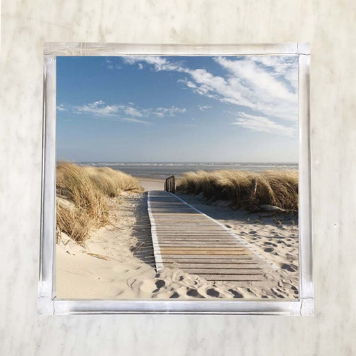 Wooden boardwalk leading through sand dunes to the beach with blue sky and ocean in the background