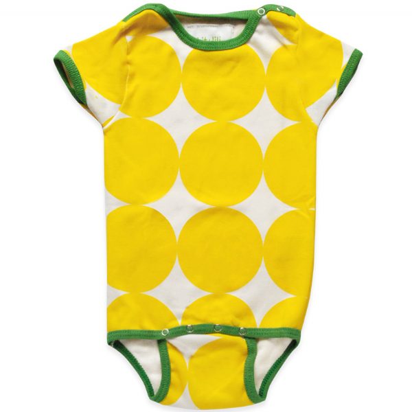 A selection of colorful onesies hanging on a wooden fence, each with a different pattern: one has blue waves, another is pink with hearts, and the last one is yellow with circles.