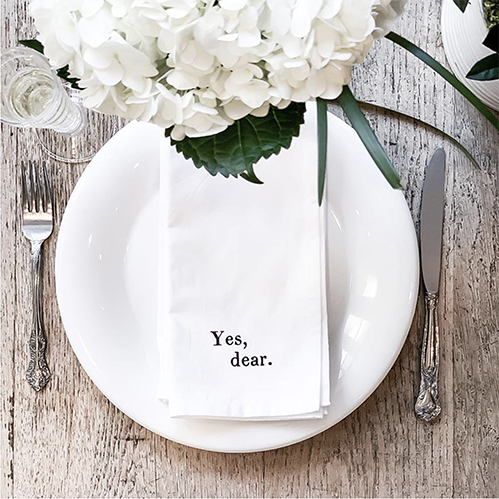 Yes Dear cotton hand towel folded on white dinner plate with white flowers, table setting