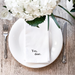Yes Dear cotton hand towel folded on white dinner plate with white flowers, table setting