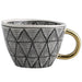 Mug with geometric black and white pattern and gold handle on a white background