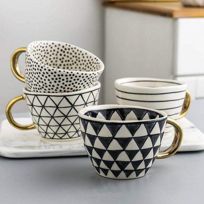 Set of patterned mugs with gold handles on a marble surface