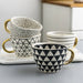 Set of patterned mugs with gold handles on a marble surface