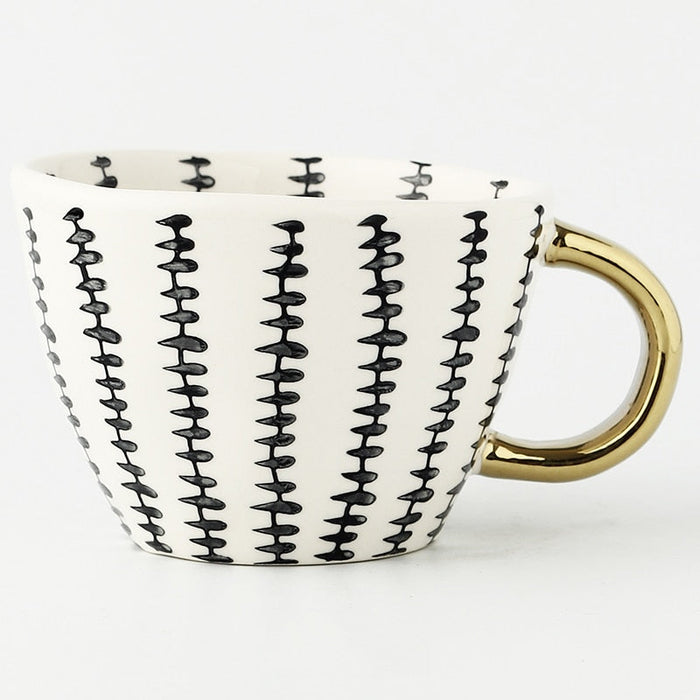 Ceramic mug with black wavy pattern and gold handle on a white background