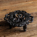 Cast iron flower-shaped tea light candle warmer stand with scroll detailing on wooden surface