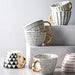 Set of patterned mugs with gold handles on a light gray background