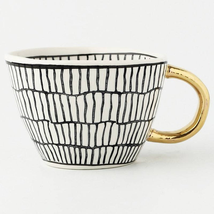 Mug with black and white striped pattern and gold handle on a white background