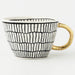 Mug with black and white striped pattern and gold handle on a white background