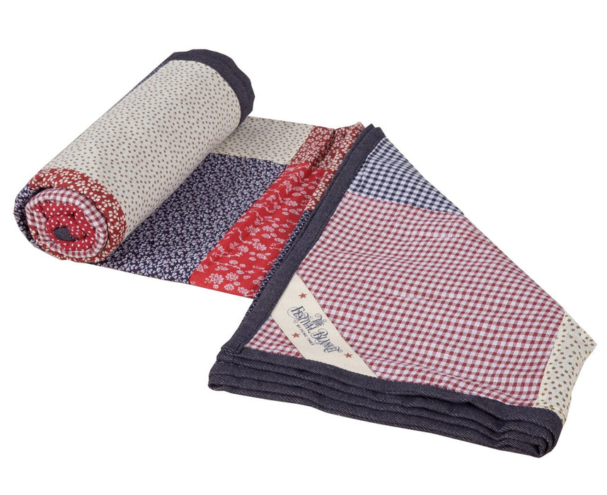 Festival Blanket — partially unrolled showing red gingham, navy, and floral patchwork panels with branded label