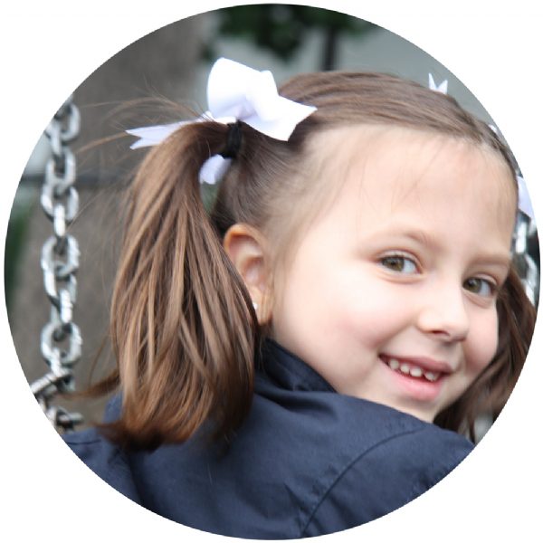 Girl wearing white bow ponytail bands in pigtails – handmade girls hair accessory from Modern Lola