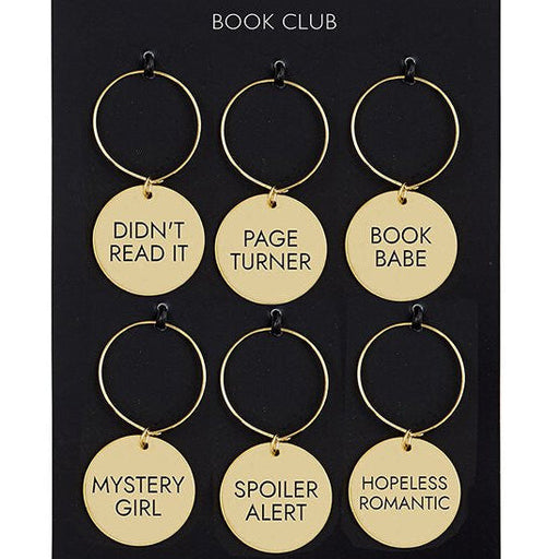 Set of gold wine charms with humorous sayings on a black card, branded as Santa Barbara Design Studio Book Club.