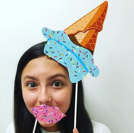 Woman holding printable ice cream photo props including a large sprinkled cone and lips in front of her face