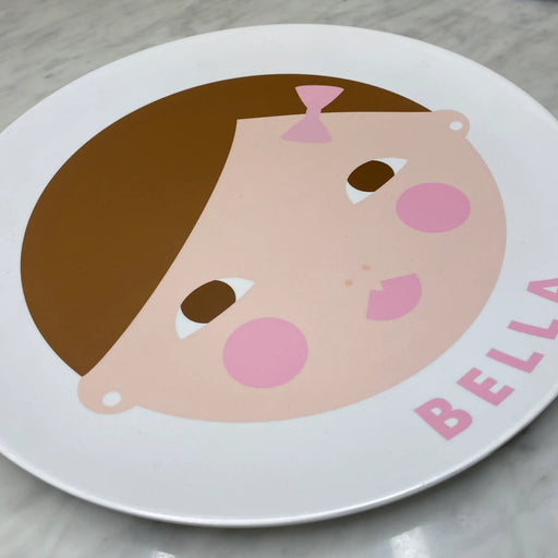 kids personalized melamine plate with a stylized face design and 'Eloise' text on a table setting.'BELLA' 