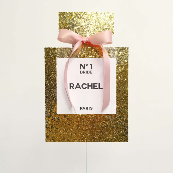 Custom gold glitter perfume bottle cake topper with pink ribbon and personalized label — bridal shower party decoration