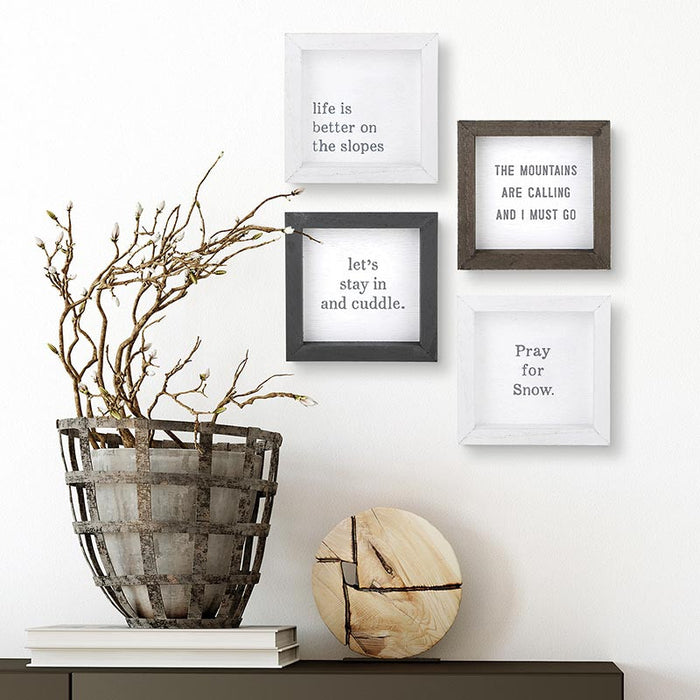 Framed quotes on a wall with decorative elements including branches and a wooden disc.