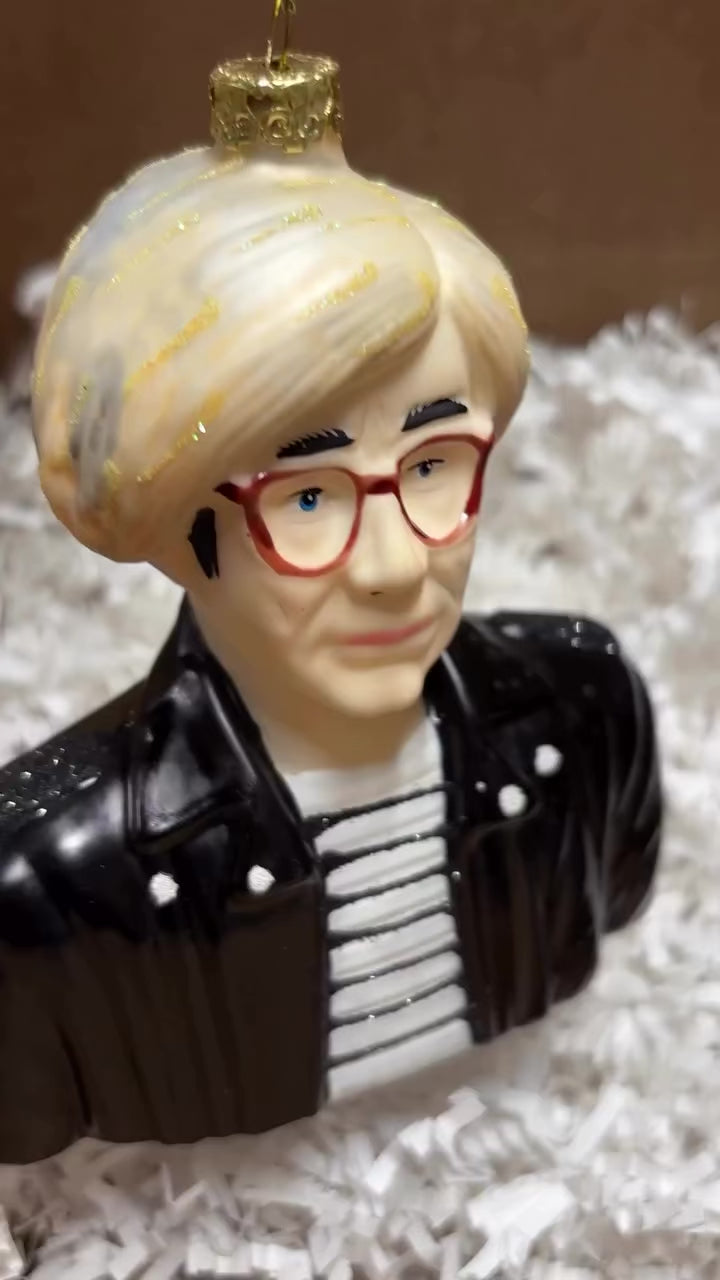 Andy Warhol glass Christmas ornament with silver hair, glasses, striped shirt, black jacket, and glitter details