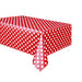 A red plastic table cover with white polka dots laid out on a table.