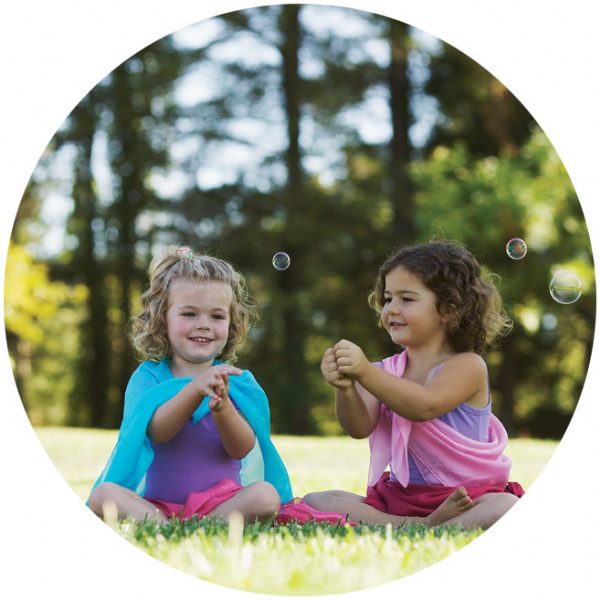 Two girls playing with colorful playsilks outside — imaginative play toys Modern Lola
