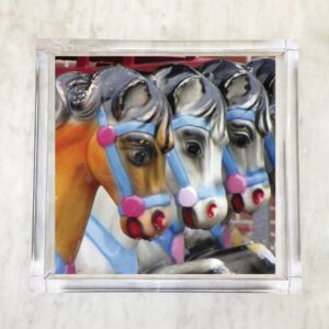 Paper napkin featuring a close-up of colorful carousel horses lined up in a row with vibrant harness details